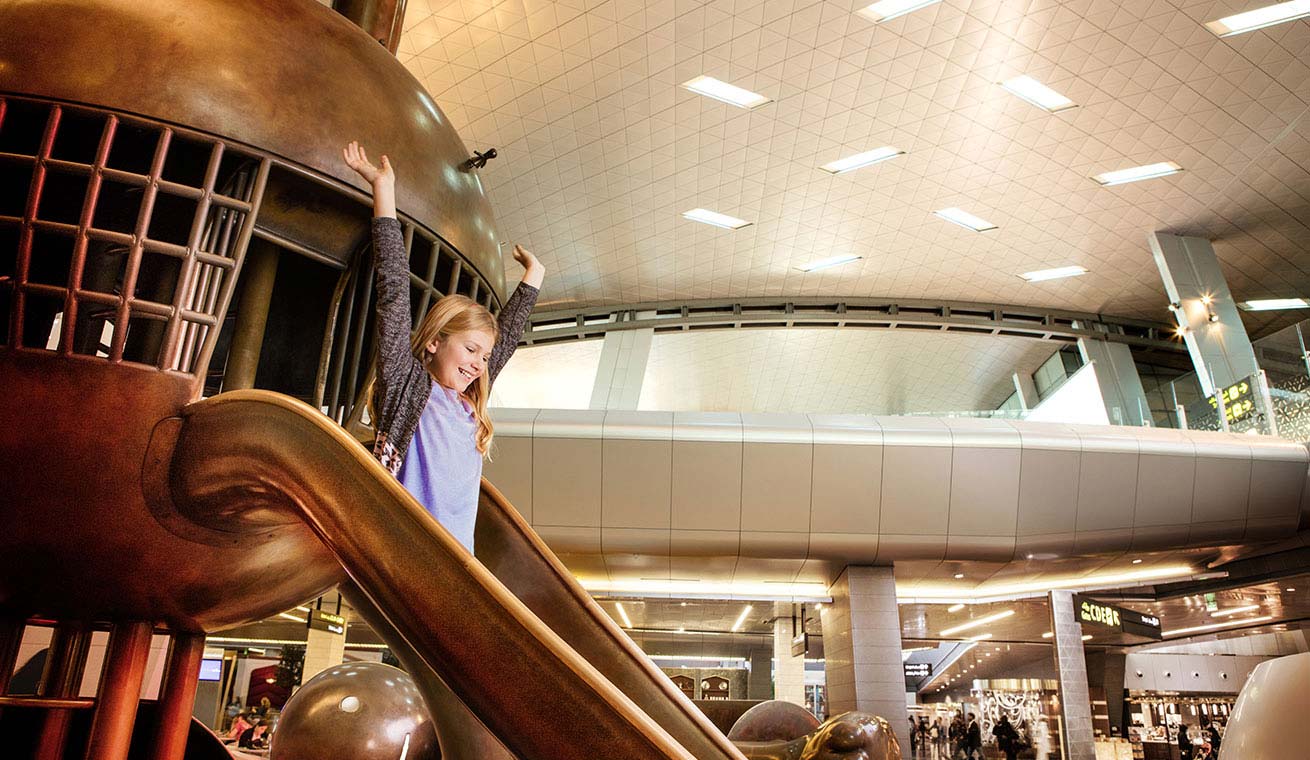 Image of a young traveller going down a slide at Hamad International Airport