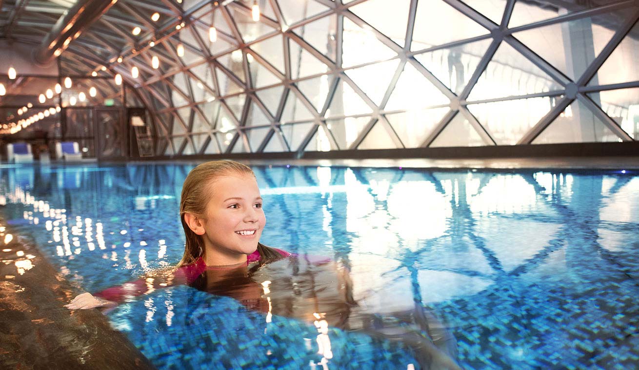 Image of a young traveller swimming at the pool at Hamad International Airport