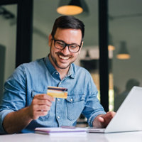 Happy cheerful smiling young adult man making online payment.